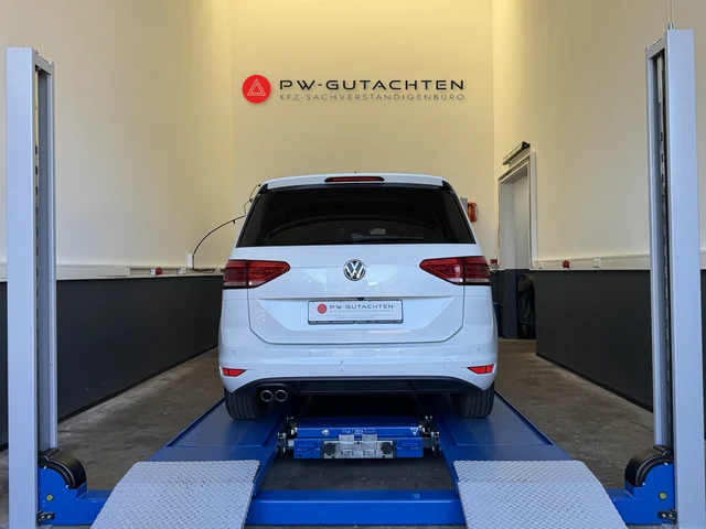VW Touran bei einer Fahrzeugbesichtigung in der Werkstatt mit PW-Gutachten-Logo