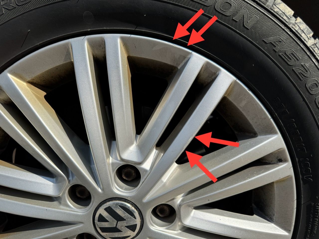 Nahaufnahme einer VW-Felge mit roten Pfeilen an Felgenrand und Speiche